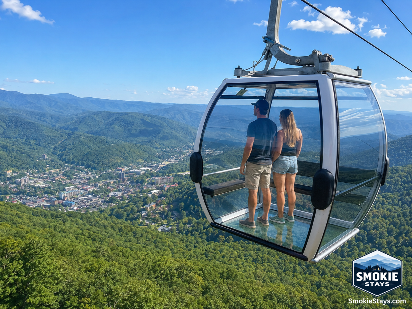 Passengers inside Anakeesta's Crystal Express all-glass gondola ascend 600 feet above downtown Gatlinburg, Tennessee, with sweeping panoramic views of the Smoky Mountain ridgeline visible through the transparent glass floor and walls.
