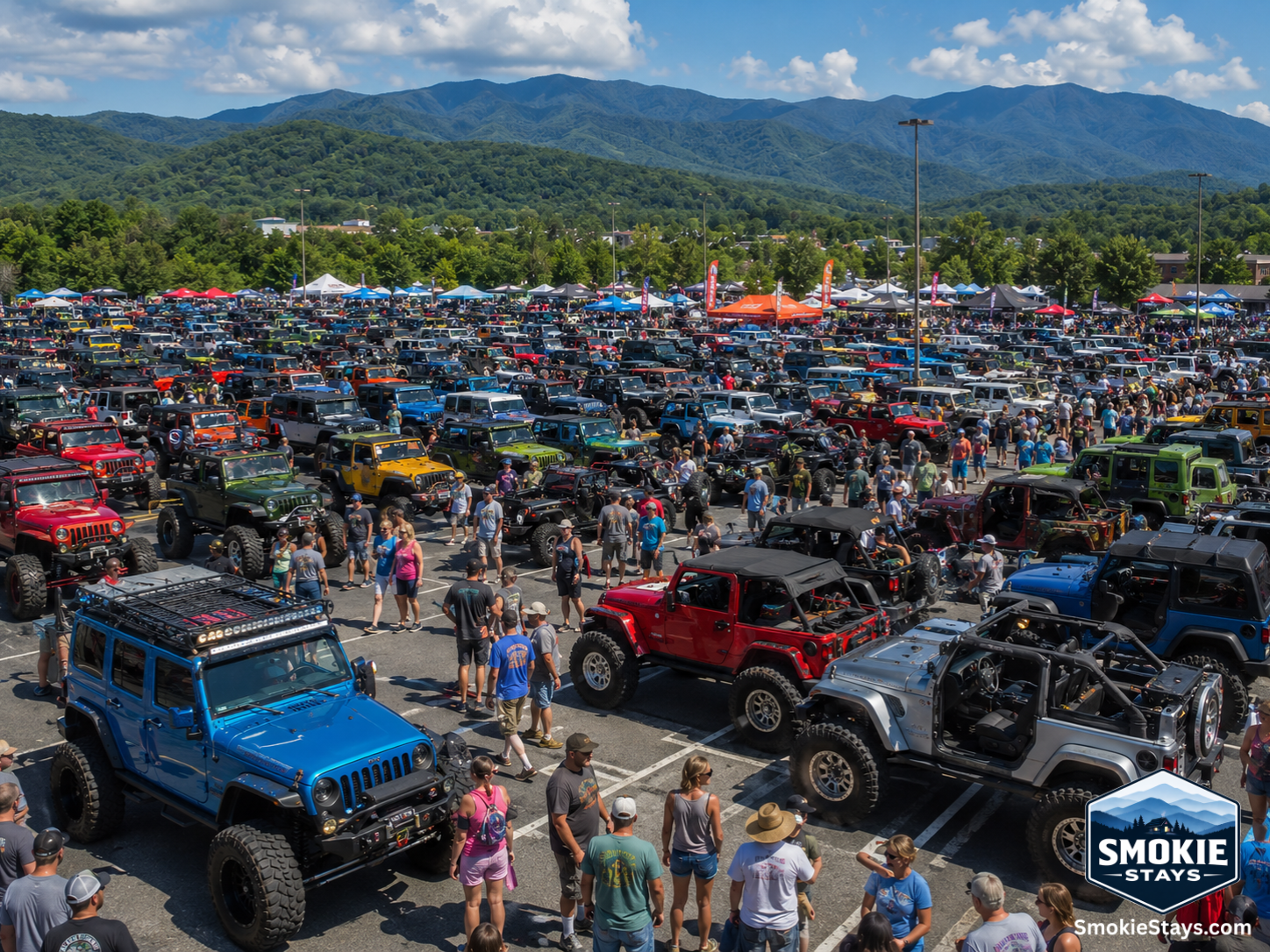 Rows of customized Jeep Wranglers and off-road vehicles fill an outdoor lot at the Smoky Mountain Jeep Invasion in Pigeon Forge, Tennessee, with crowds browsing vendor booths and the Smoky Mountains in the background.
